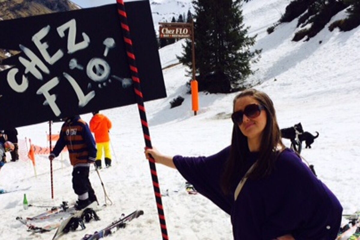 a woman holding a flag saying chez flo in avoriaz