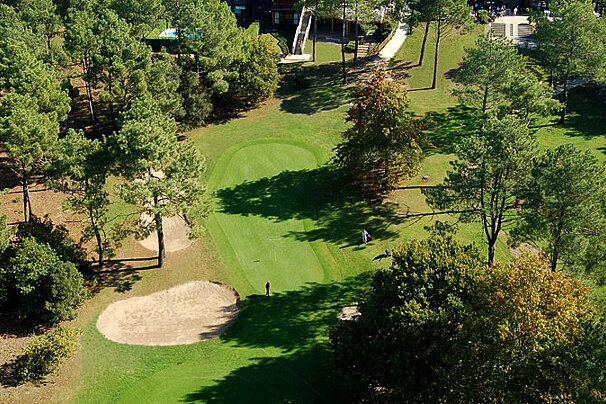 green golf course with trees and sand bunker