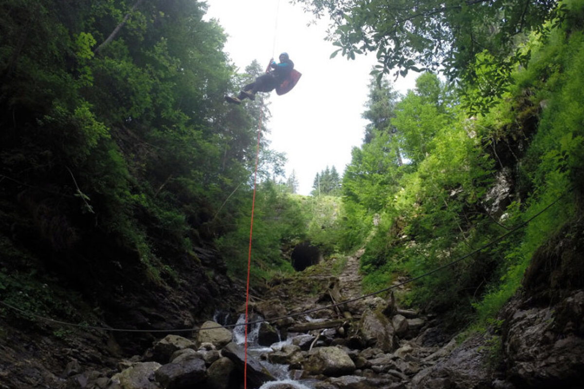 a man descending a rope into a river gully