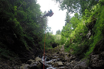a man descending a rope into a river gully