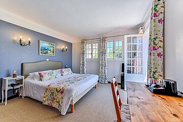 A hotel room with a king size bed and floral curtains