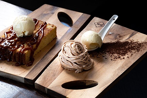 A wooden cutting board with a piece of cake and a scoop of ice cream on it