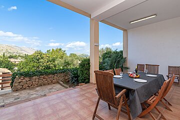 A patio with a table and chairs and a view of mountains