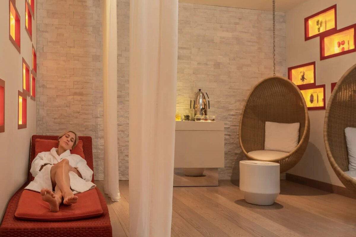 A woman in a bathrobe is laying on a lounge chair