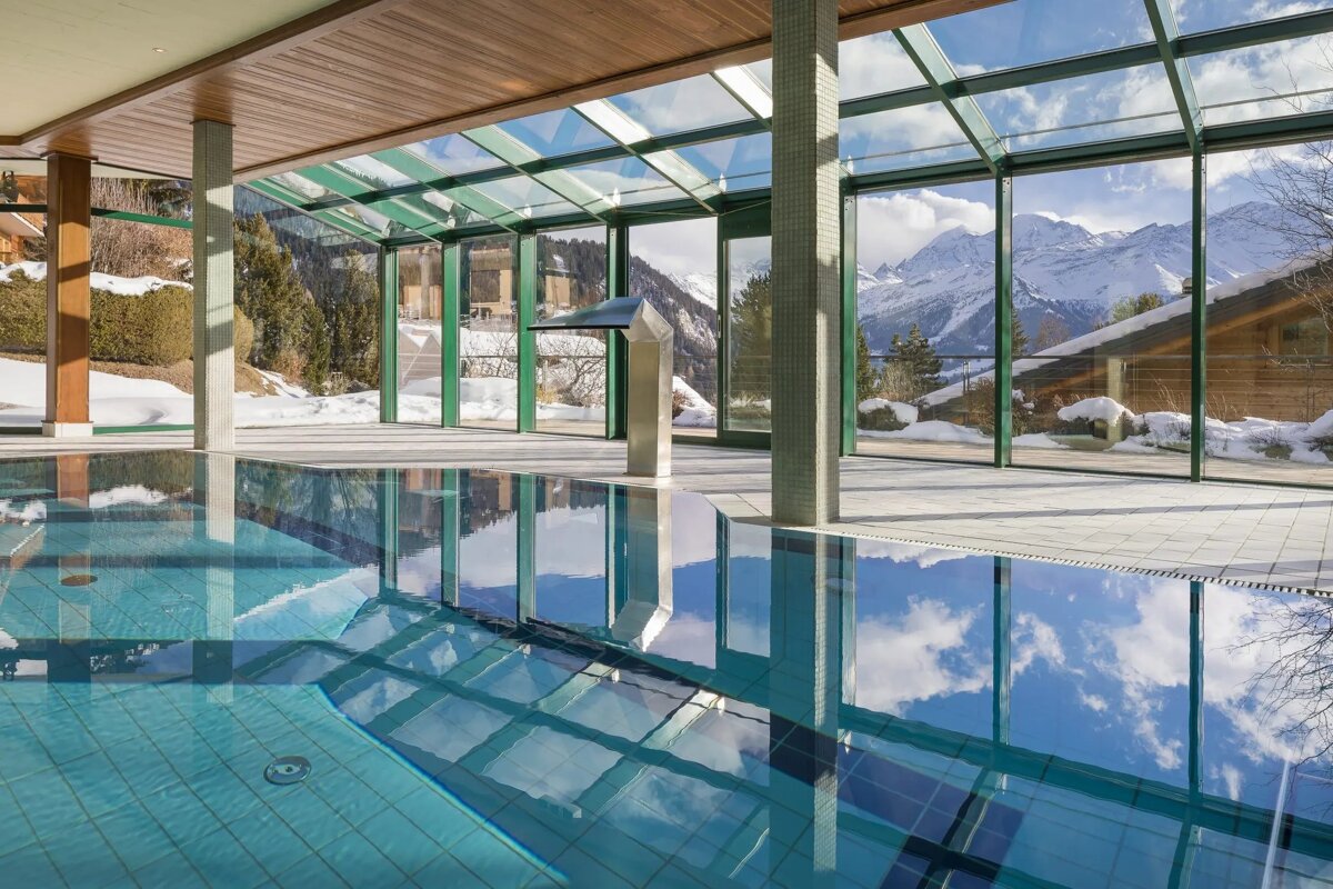 A large indoor swimming pool with mountains in the background