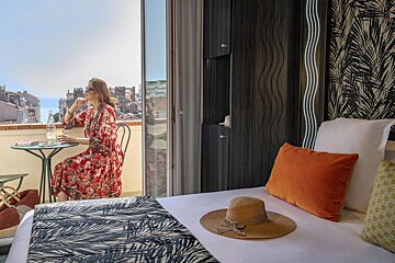 A woman in a red dress sits at a table on a balcony