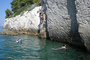 a woman climbing on rocks above the sea