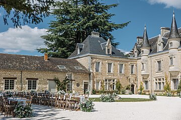 Tables and chairs are set up in front of a large stone building
