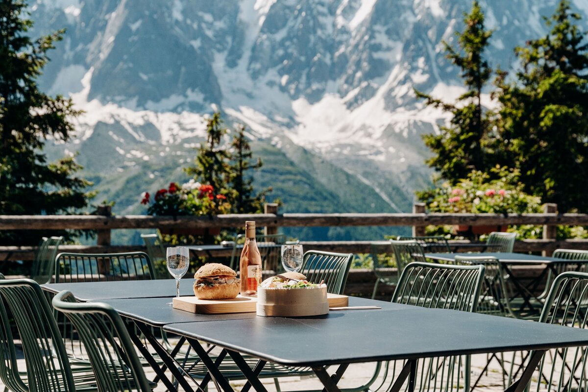 A bottle of rose wine sits on a table with a mountain in the background
