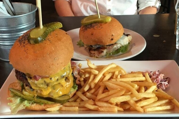 two plates of burgers in a bar