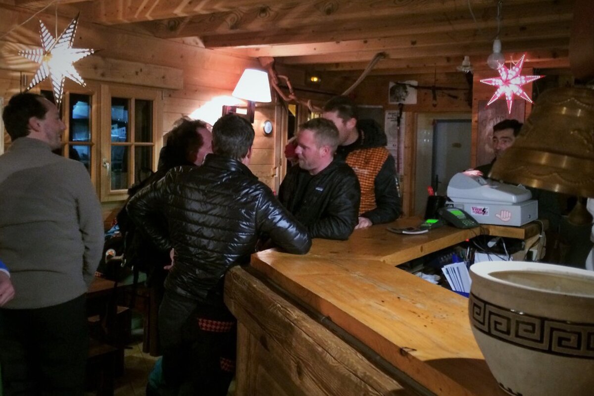 a group leaning on a bar in a mountain refuge