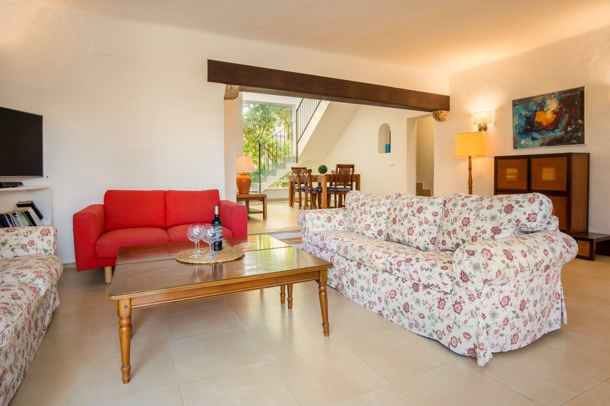 A living room with a red couch and a white floral couch