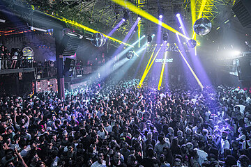 A large crowd of people are gathered in a club with a sign on the wall that says dirty squad
