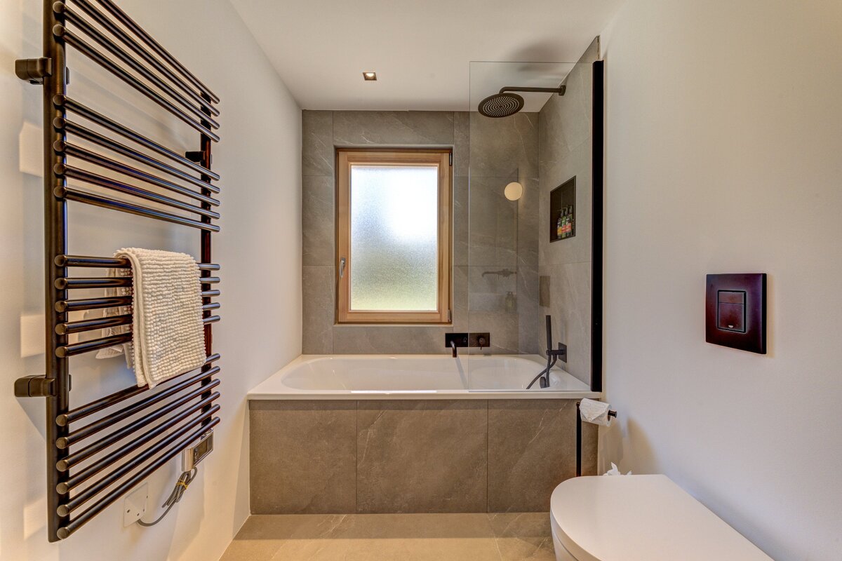 A bathroom with a bathtub a toilet and a window