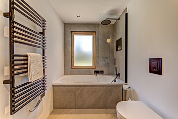 A bathroom with a bathtub a toilet and a window