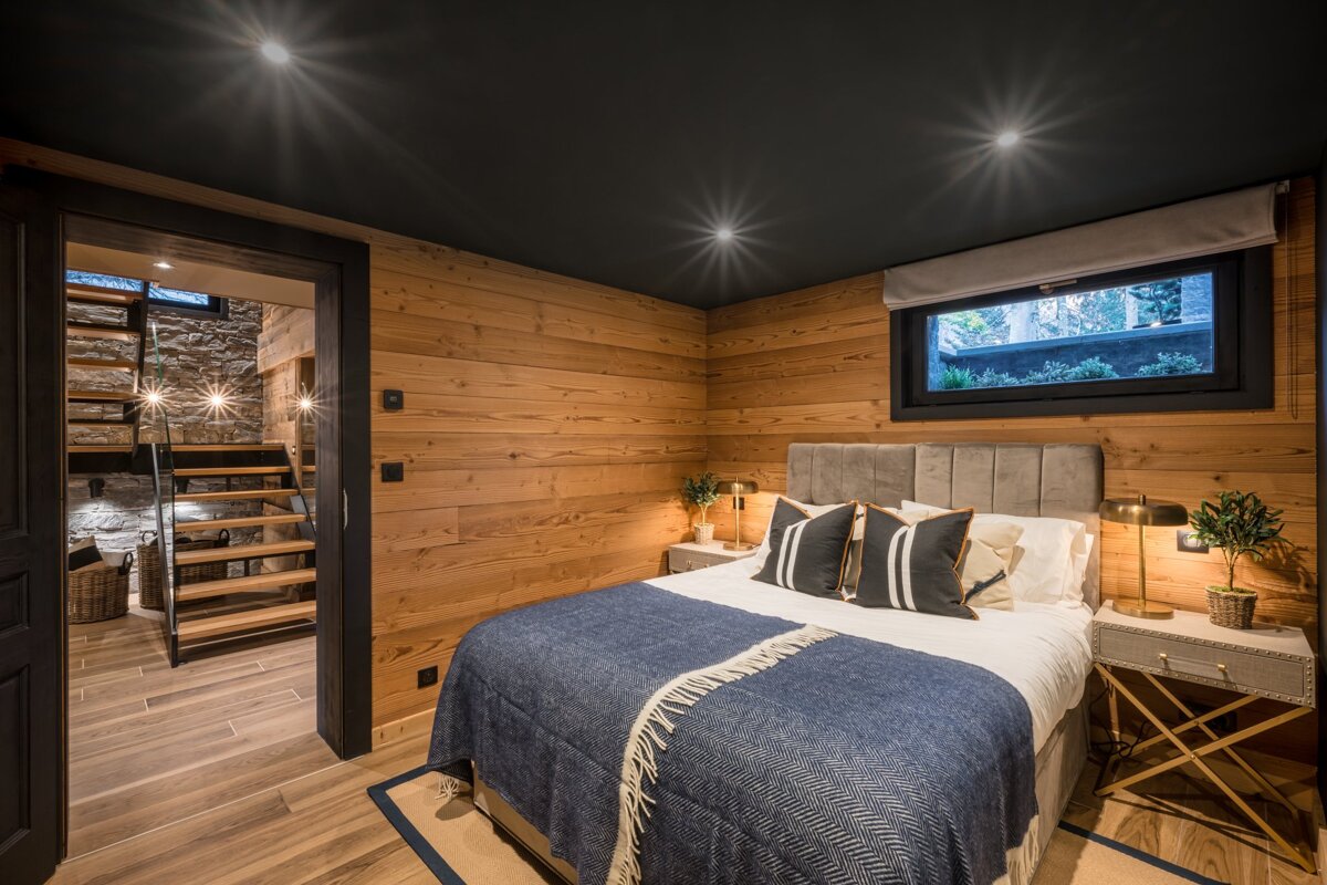 A bedroom with wood paneling and a large bed