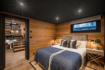 A bedroom with wood paneling and a large bed