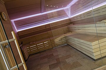A sauna with wooden benches and a glass door