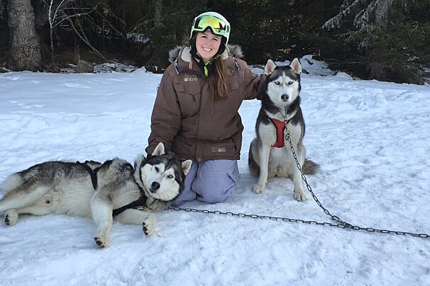 a woman stroking two husky dogs