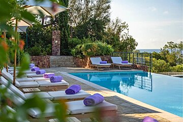 A swimming pool with purple towels on the lounge chairs