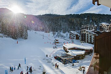 Skiers are gathered on a snowy slope with a sign that says 