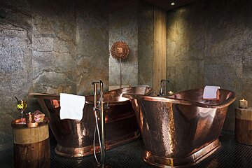 Two copper bathtubs in a bathroom next to each other
