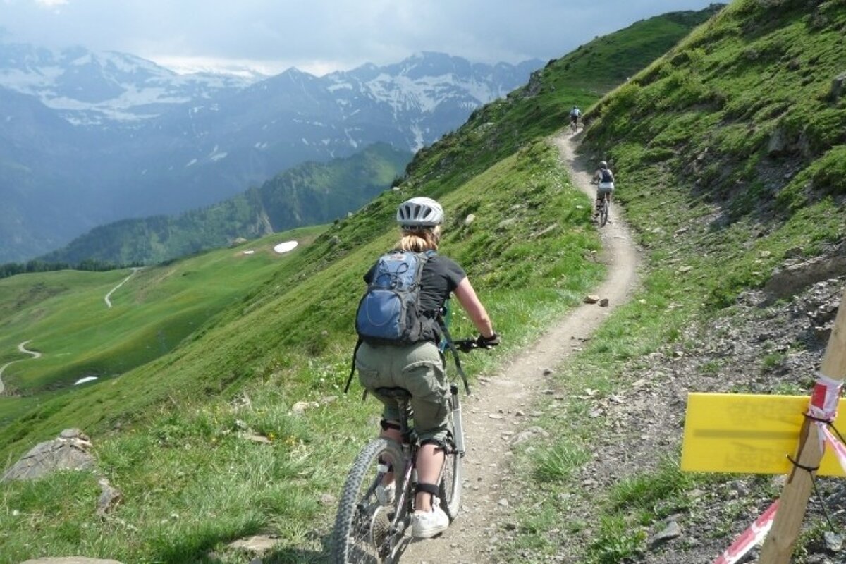 a picture of a woman on a mountain bike going along a trail