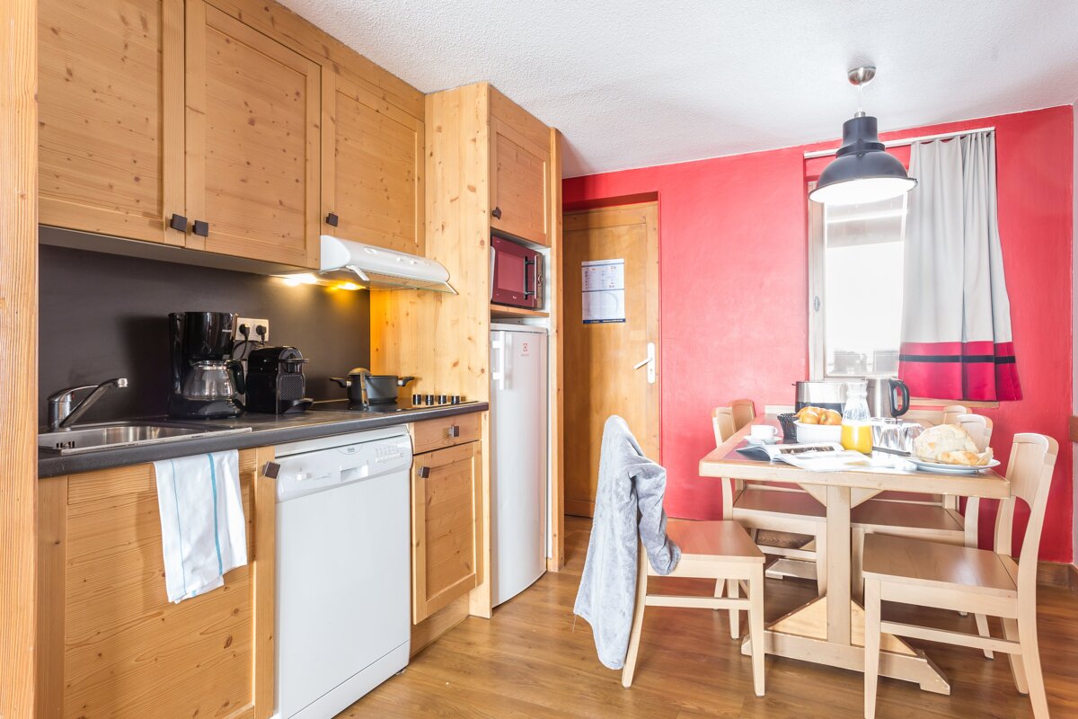A kitchen with wooden cabinets and a red wall