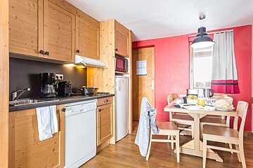 A kitchen with wooden cabinets and a red wall