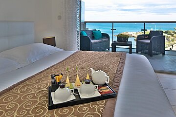 A hotel room with a large bed and a balcony overlooking the ocean