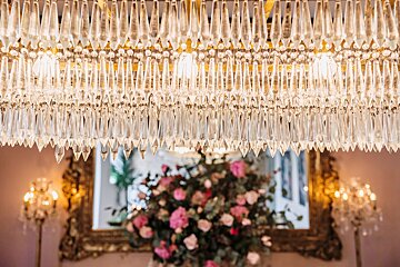 A chandelier hanging from the ceiling with a vase of flowers in the foreground
