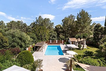 A large swimming pool surrounded by trees and umbrellas