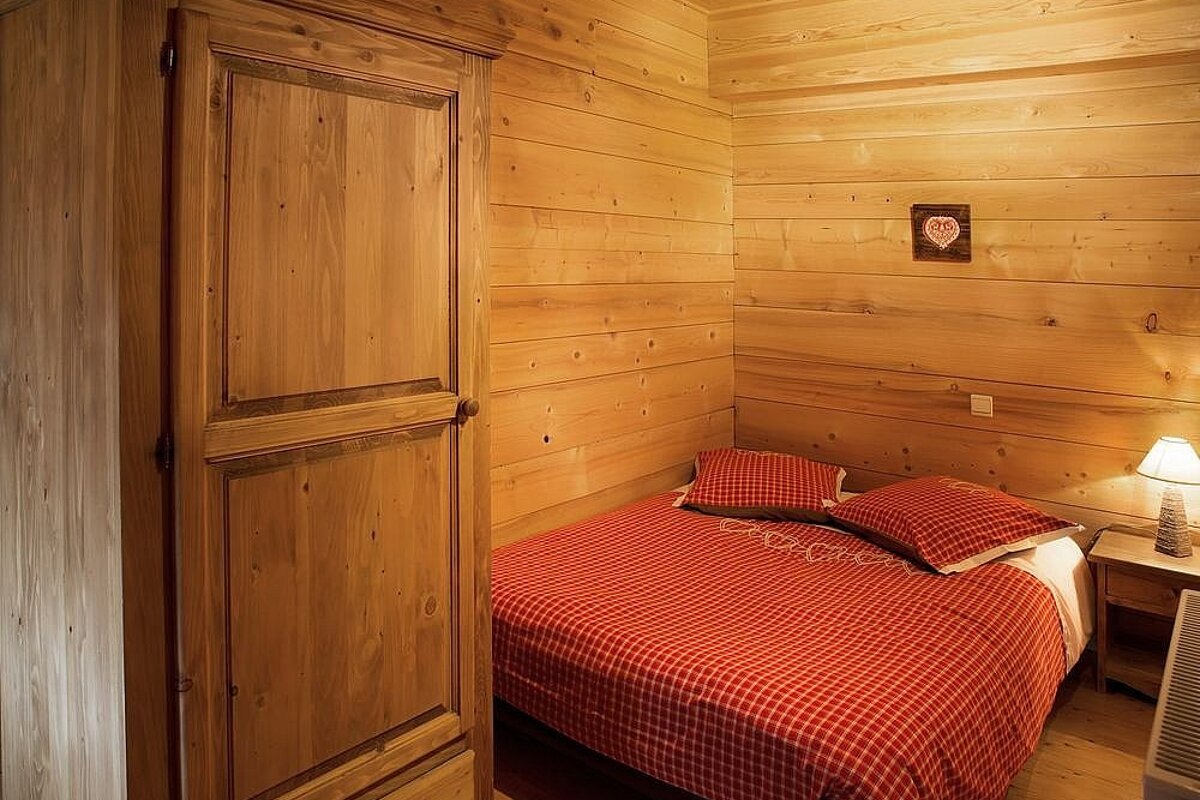 A bedroom with a bed and a wooden cabinet
