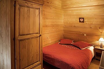 A bedroom with a bed and a wooden cabinet