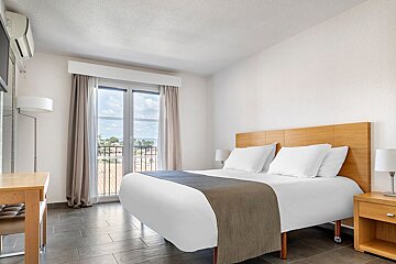 A hotel room with a king size bed and a balcony