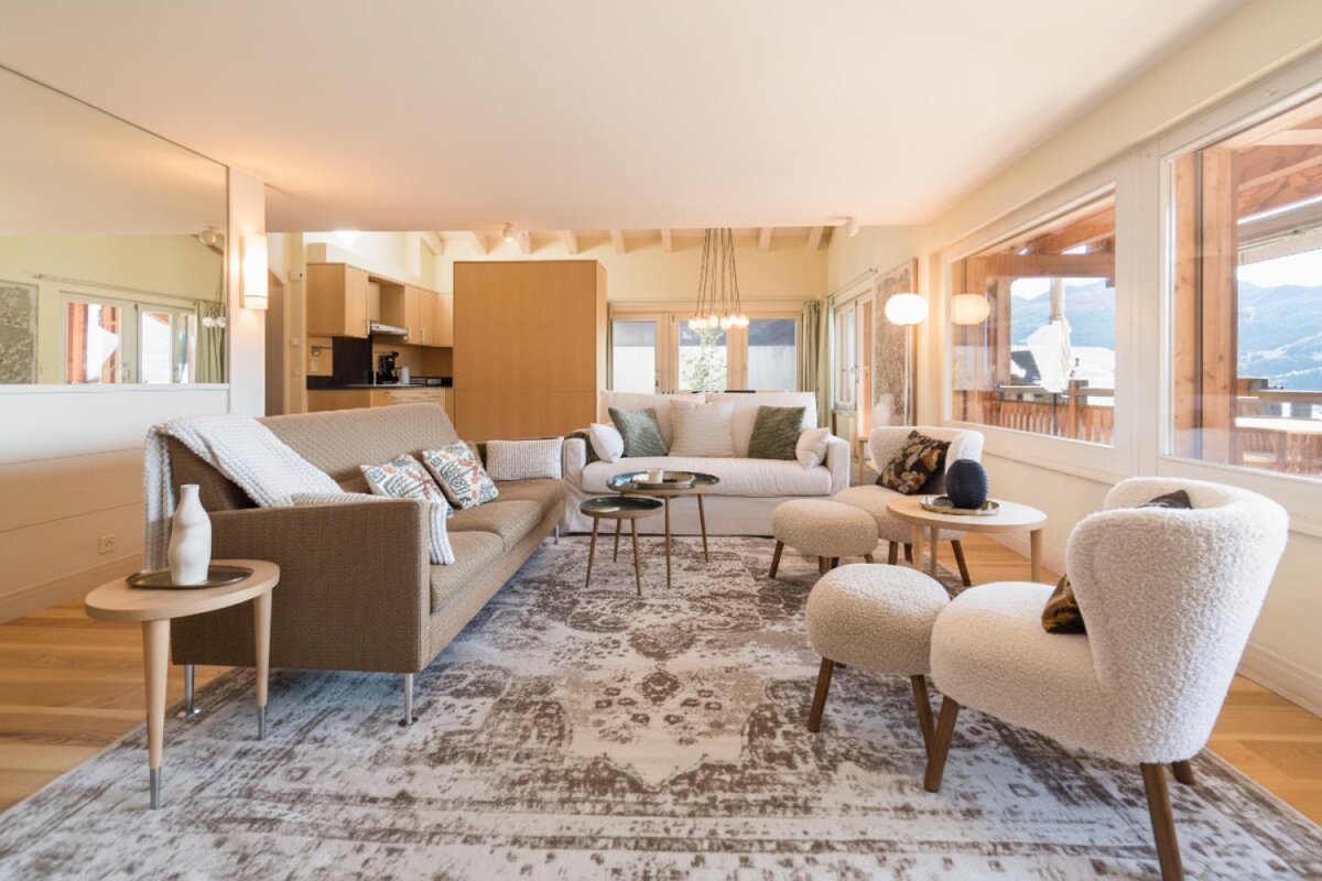 A living room with a couch and chairs and a rug