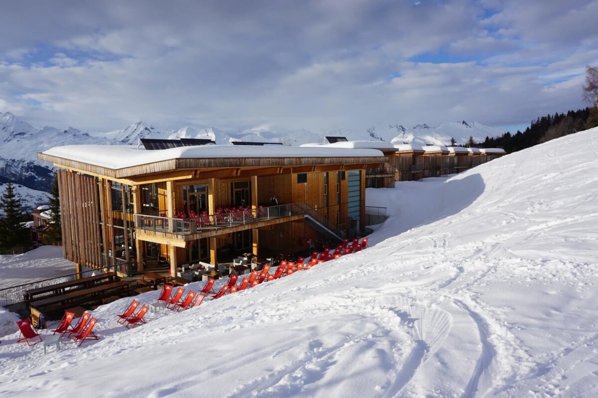 A row of red chairs sit in front of a snow covered building