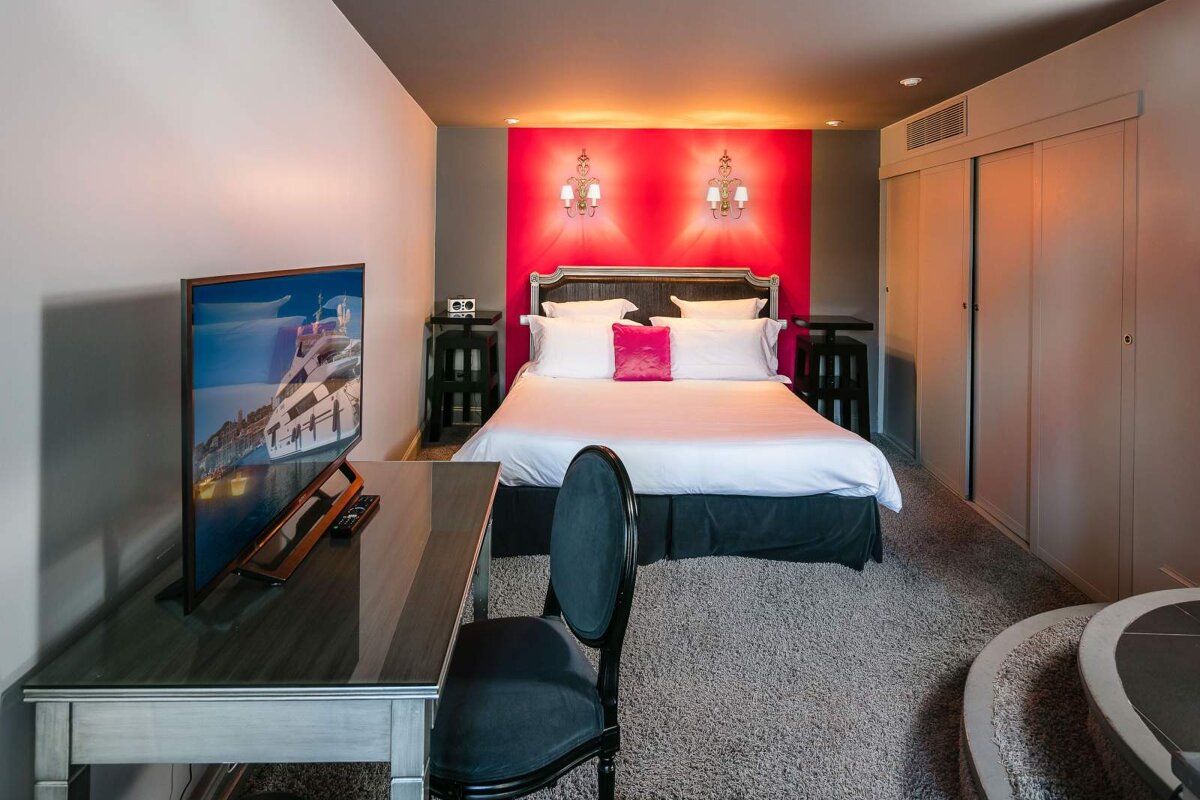 A hotel room with a bed a desk and a flat screen tv