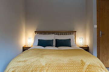 A bed with a yellow blanket and blue pillows