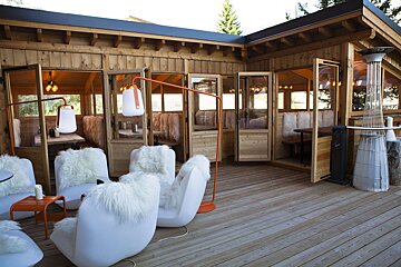 A wooden building with white furry chairs and lamps