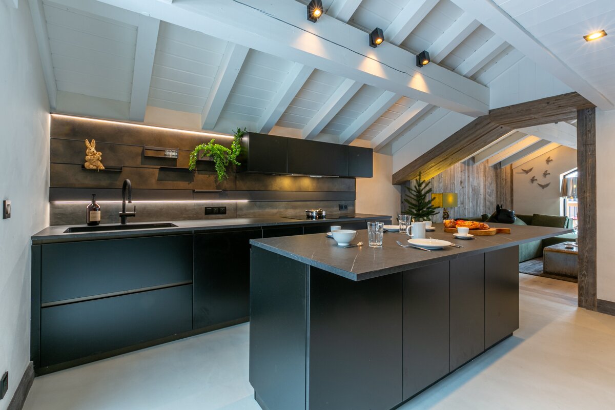 A kitchen with black cabinets and a large island