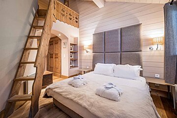 A bedroom with a bed and a wooden ladder