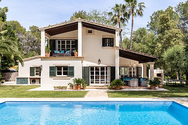 A white house with a large swimming pool in front of it