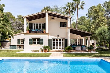 A white house with a large swimming pool in front of it