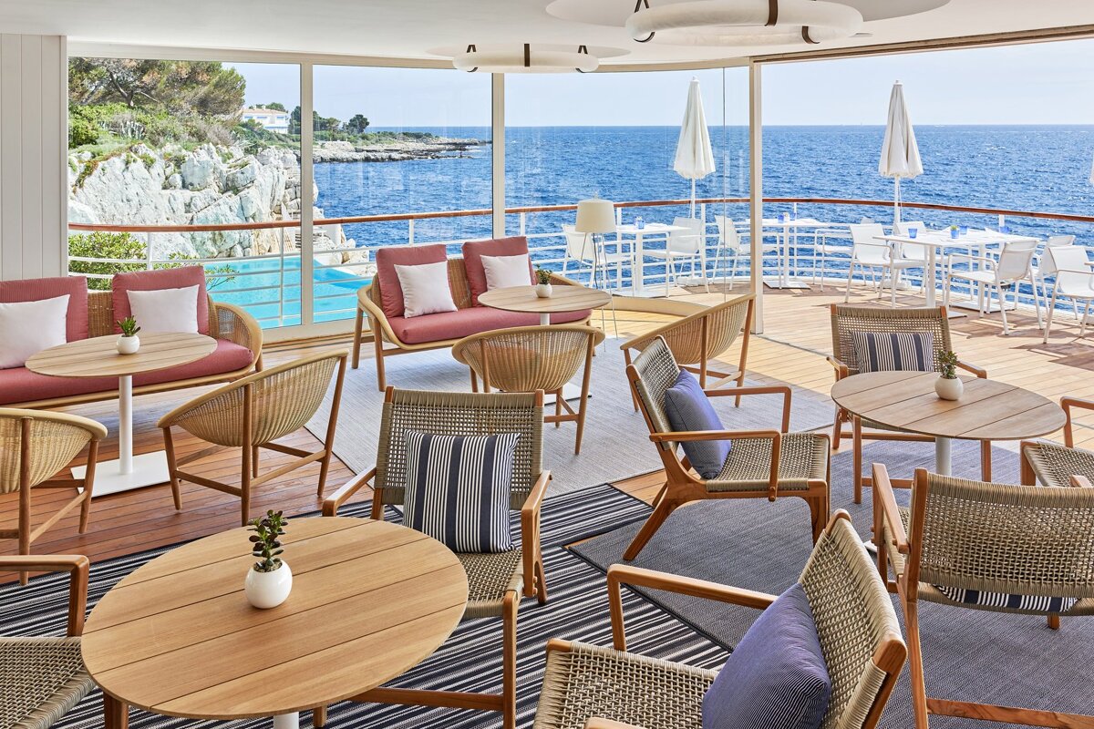 A restaurant with tables and chairs overlooking the ocean