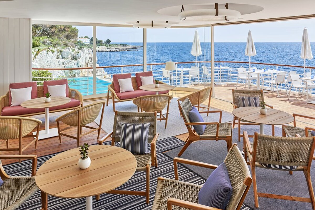 A large room with tables and chairs overlooking the ocean