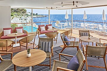 A large room with tables and chairs overlooking the ocean