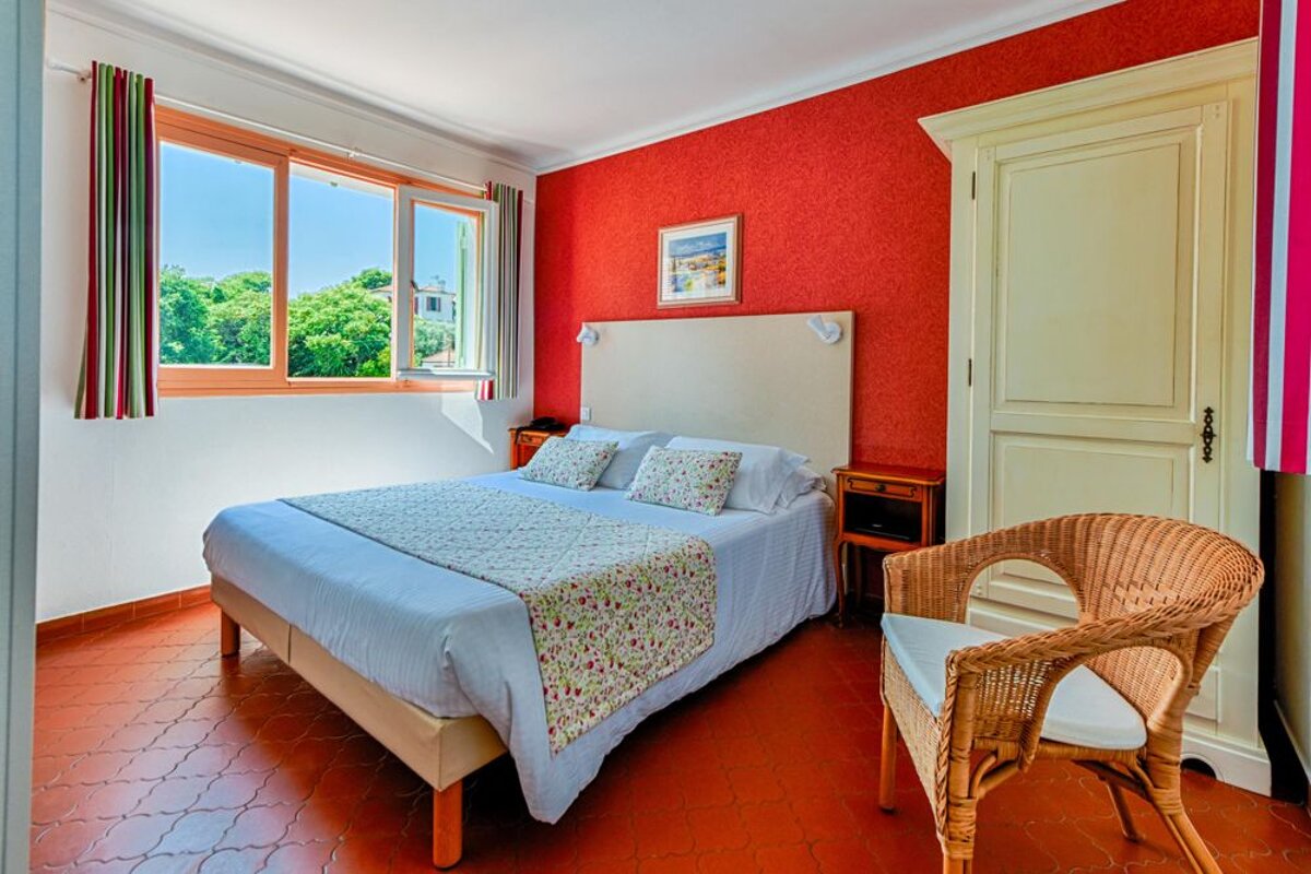 A bedroom with a large bed and a wicker chair