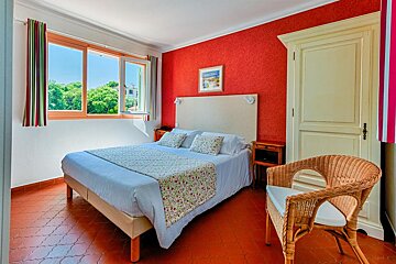 A bedroom with a large bed and a wicker chair