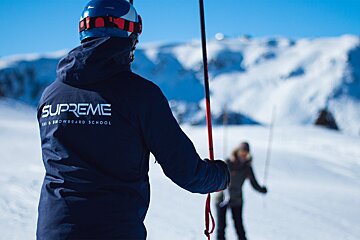 A person wearing a supreme ski and snowboard school jacket